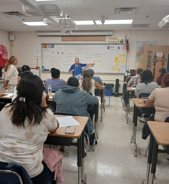 principal and teacher standing in front of seated students in classroom