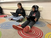 students work on laptops in class