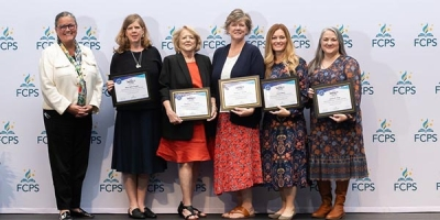 Superintendent standing with staff while they hold certificates