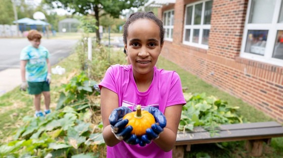 student smiles with a pumpkin