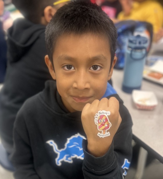 A boy holds his hand up with a sticker on it 