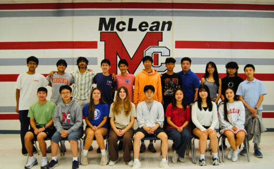 A group of seventeen young people posing in front of a wall mural with the text "McLean" and large letters "MC."