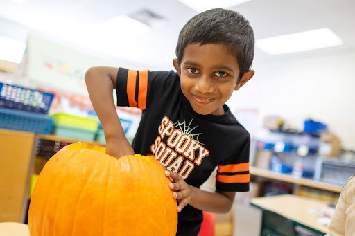 student carving a pumpkin