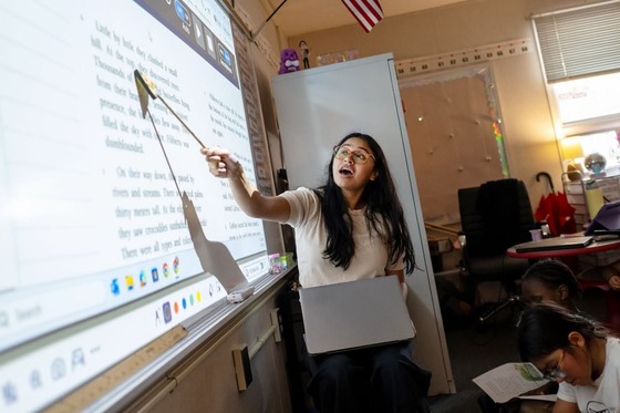 teacher points to the whiteboard while giving a lesson