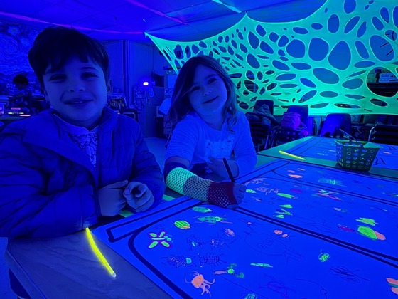 students drawing bugs under black light 