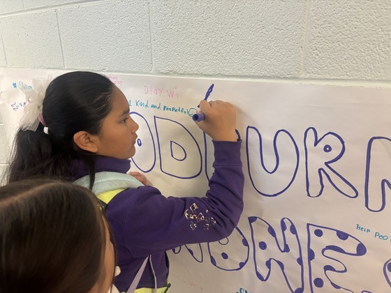 A girl signs a kindness banner
