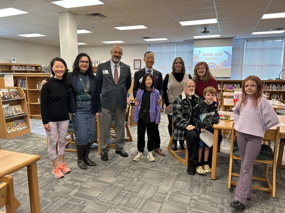 A group of Veterans stand with students, parents, and school administrators 