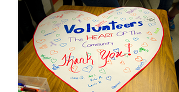 Heart-shaped poster with "Volunteers: The HEART OF The Community. Thank You!" and colorful decorations and signatures.
