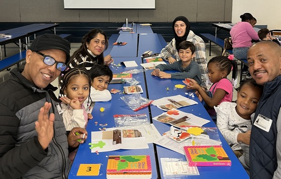 PreK families sitting at tables in the cafeteria with books and craft supplies