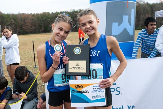 two students smiling at a track meet with their medals