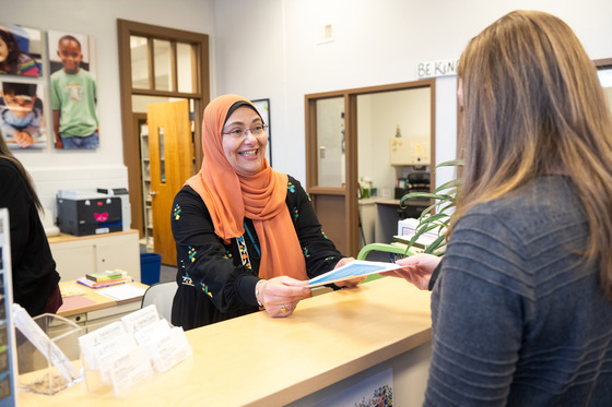 Amal hands a piece of paper to parent