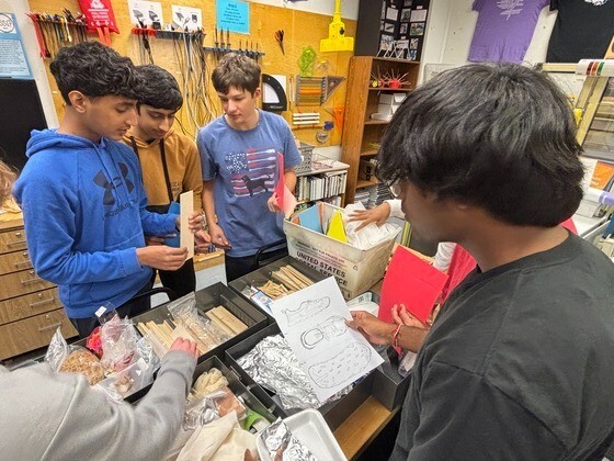 Students standing at table reviewing designs