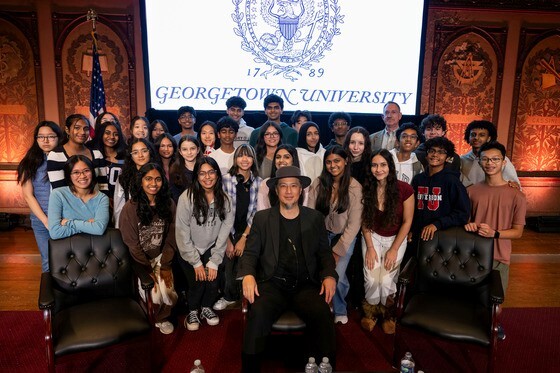 students standing behind seated professor