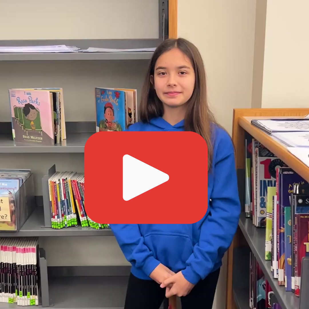 A female student standing in front of library stacks