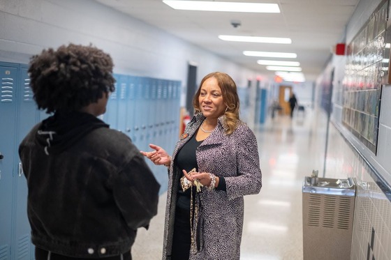 teacher smiles while talking to a student in the hallway