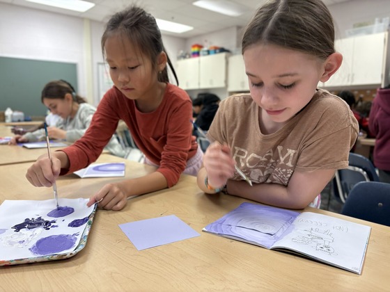 two students painting in art class