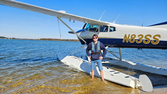a student standing in front of a plane parked on the water