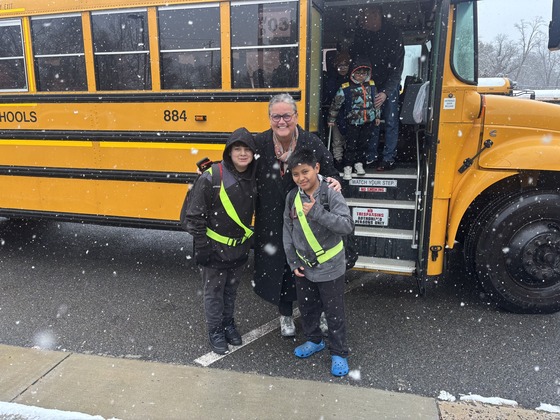 Dr. Reid poses with two safety patrols in front of a bus 