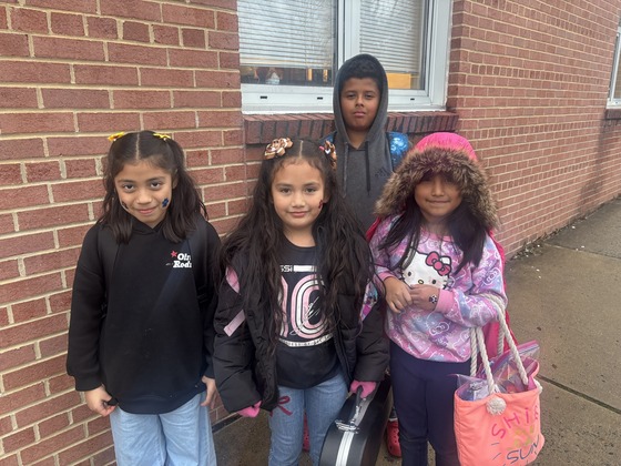 Students wear their paw print stickers in front of the building 