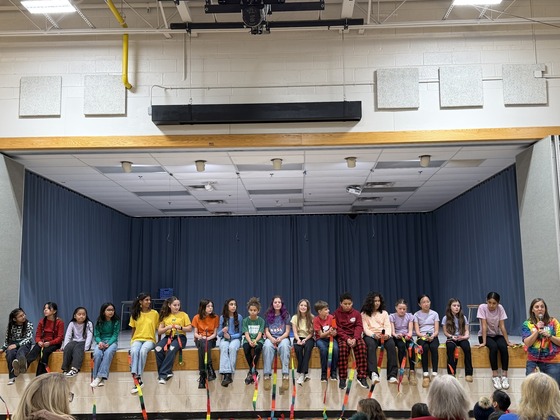 Students sit on the edge of the stage for a drama club production 