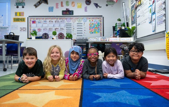 students smiling as they sit on the carpet