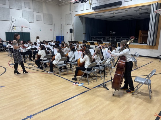 Students sit with their string instruments  