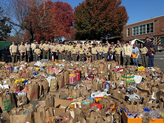 Pack and Troop 150 standing behind the bags of food collected during their food drive