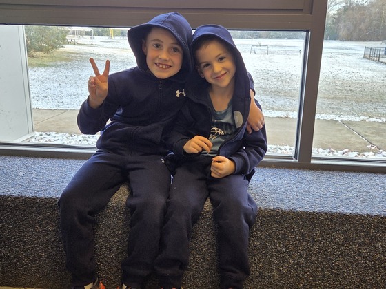 Two students sitting together in front of a classroom window with wintry background outside.