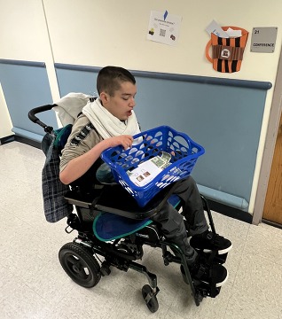 Student in wheel chair with basket of order forms on lap 