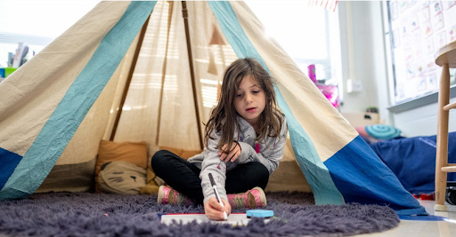 student sits on the floor while working an a writing project
