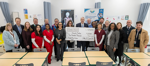 a group of people smile while they hold a large check