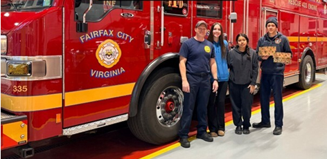 high school students standing beside first responders holding baked goods