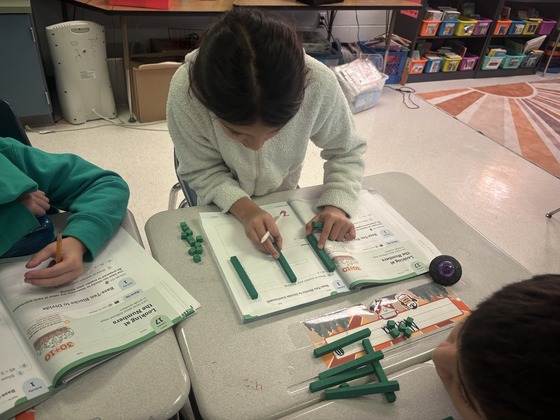 4th Grade student uses math materials to figure out a problem 