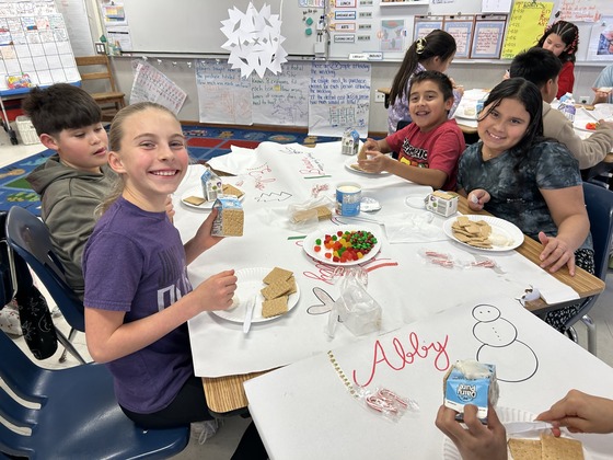 Students smile as they make their gingerbread house 