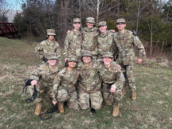Students wearing military fatigues standing and kneeling together.