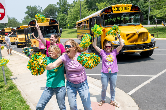 teachers cheering outside of school with pom poms on the last day of school