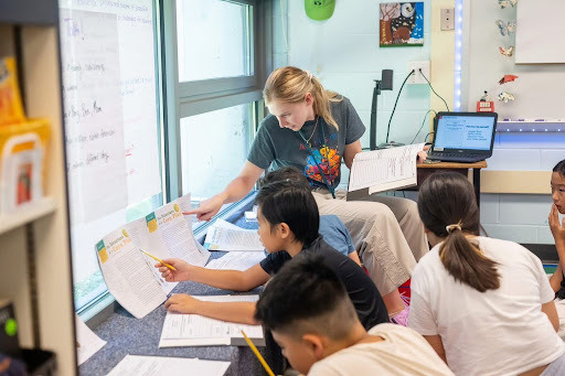 teacher helps a student with a problem on paper