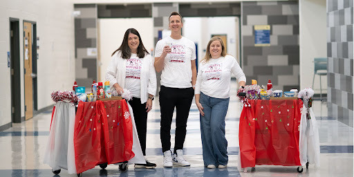 three administrators smile next to their carts full of sweets