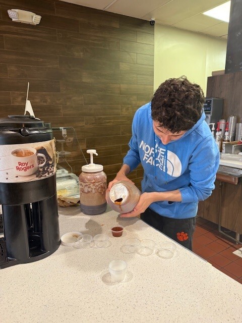a student pouring sauce into cups
