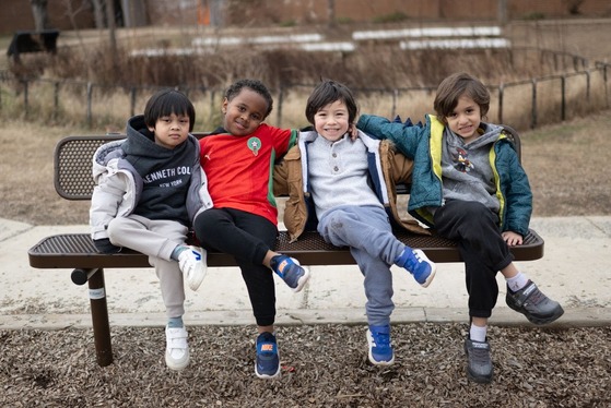 students sitting on a bench with their legs crossed smiling for a photo