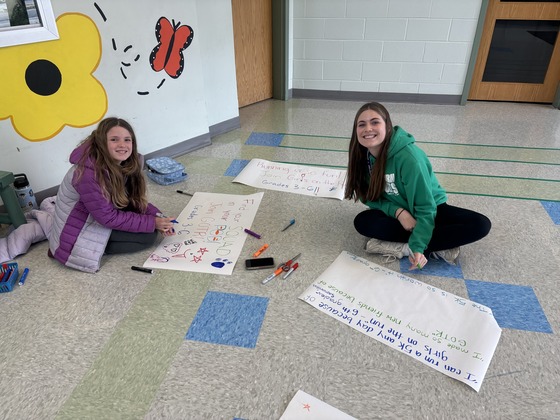 A teacher and student make posters to promote a club