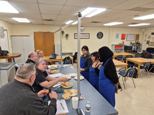 Student standing in front of adult seated panel