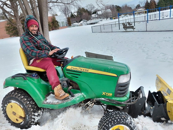 Photo of Mr. Leo operating the snow plow tractor clearing the sidewalk after the big snow storm.