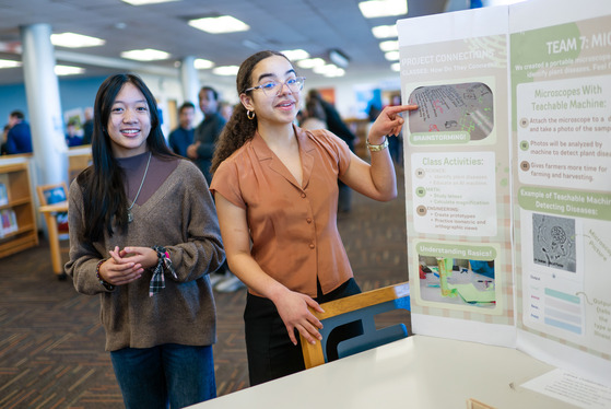 students smiling next to their science project trifold poster board