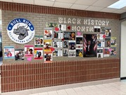 Pictures of famous Black historical figures hanging on a wall, with a sign saying "Black History Month"