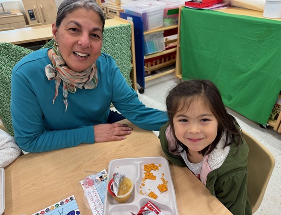 A teacher and a student sitting at a table eating snack