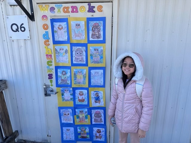Student standing in front of a door decorated with Woodchuck artwork.