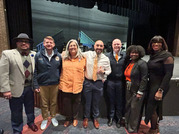 photo of individuals in a line in front of a stage