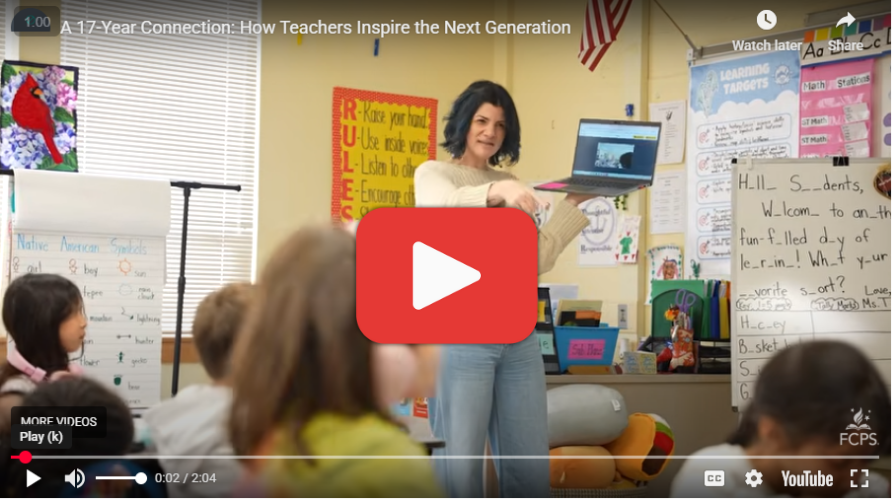 Teacher showing a laptop screen to a classroom of elementary students during a tech lesson.