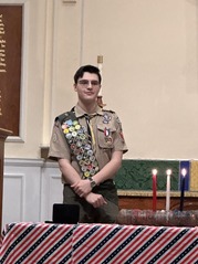 A student wearing an Eagle Scout uniform poses on stage.